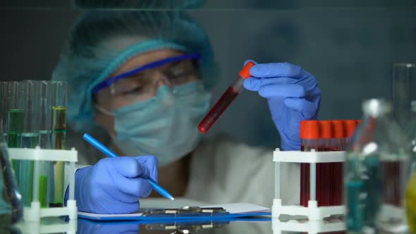 Scientist Checking Tube With Blood Analysis and Making Notes, Epidemic Outbreak