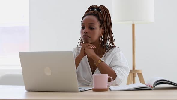 Young African American Woman is Working with Laptop at Table in Light Office Spbi