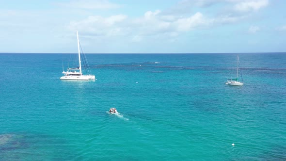 Motorboat transporting people to Catamaran for trip on Caribbean Sea during sunny day with blue wate