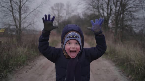 Happy Preschool Boy Making Funny Faces Looking at Camera and Running Away at Gloomy Fall Forest