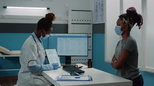 Doctor Showing Bones Anatomy on Tablet While Wearing Face Mask