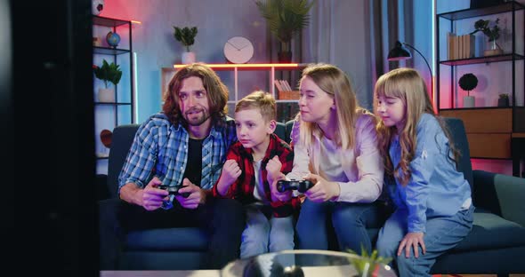 Family Having Fun Together while Parents Playing Videogames on TV Set, Their Kids