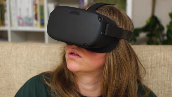 Close-up of a woman wearing virtual reality glasses sitting on the couch at home