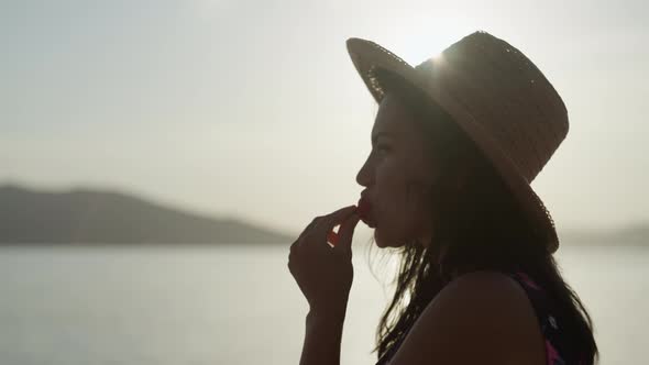 A Girl Bites a Strawberry at Sunset Near the Sea