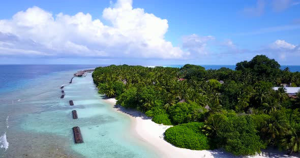 Daytime overhead travel shot of a sandy white paradise beach and aqua blue ocean background in vibra