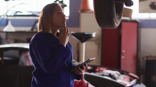 Female mechanic using digital tablet and inspecting the car at a car service station