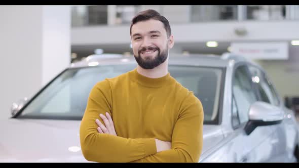 Portrait of Confident Bearded Caucasian Man in Mustard Sweater Posing in Front of White Car