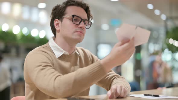 Young Male Designer Flying Paper Plan in Office