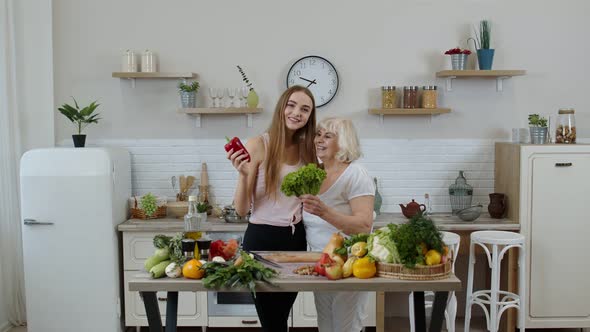 Mature Woman with Grandchild Girl Recommending Eating Raw Vegetable Food. World Vegan Day Concept