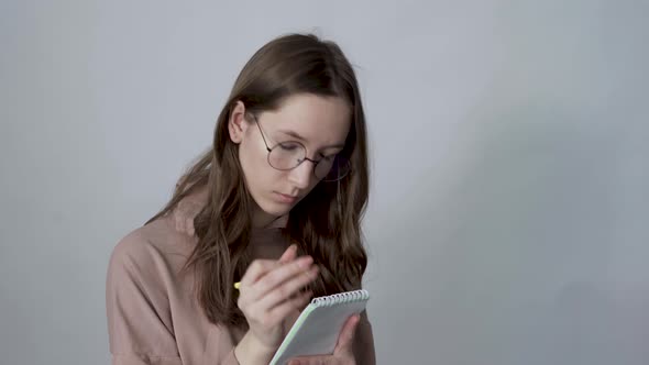 Young Inspired Woman Pensively Thinks and Making Notes in Paper Notebook