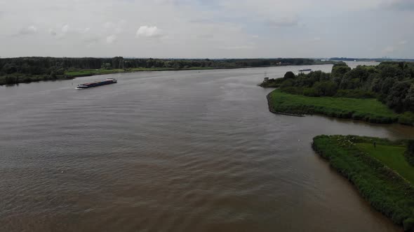 Aerial Flying Over Oude Maas In Barendrecht, With Cargo Ship In Background. Dolly Right