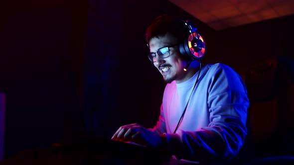 Man Gamer is Annoyed Playing Videogames on Laptop Room with Neon Lighting Side View