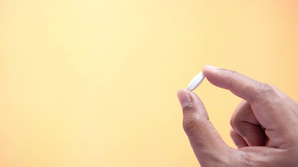 Close Up of Man Hand Holding a Single Pill with Copy Space