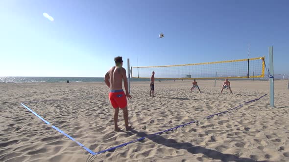 Men playing beach volleyball.