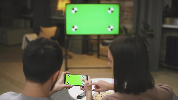 Couple Playing Football Game On Smartphone