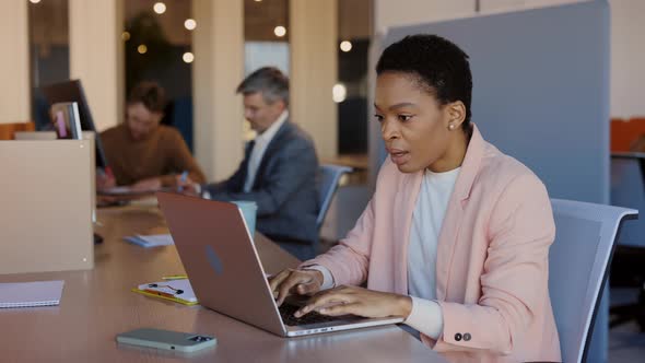 Young Multiracial Female Office Worker Rejoicing of Something While Looking at Her Modern Laptop