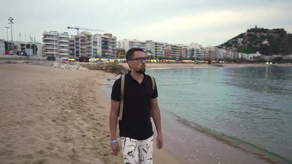 Adult Bearded Man Is Strolling on Shore of Picturesque Bay in City in Twilight