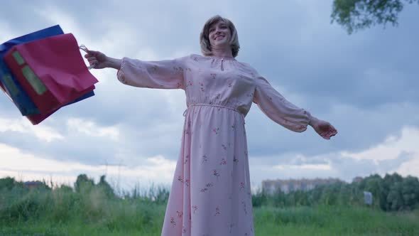 Excited Happy Transgender Woman Raising Hands with Shopping Bags Smiling Spinning Outdoors in Slow