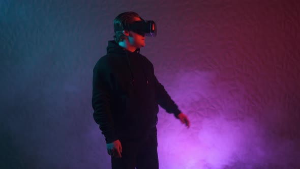Man in Black Hoodie and VR Helmet on His Head Move Left and Right and Puts His Hands in Front of Him