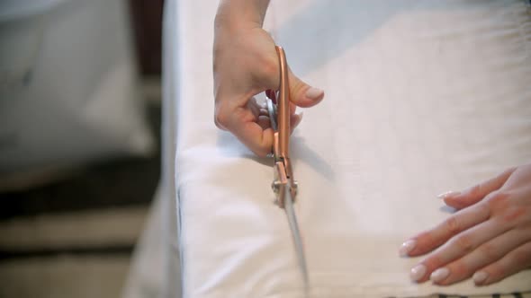 Young Woman Seamstress Cutting the Cloth Following the Mark