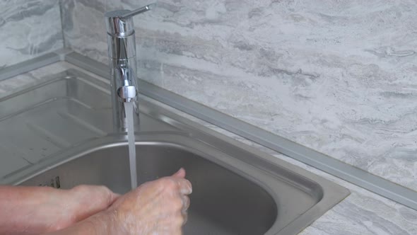 Man Washes His Hands with Soap Under the Streem at Home