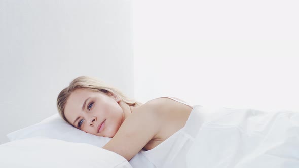 Young woman lying in the bed. Beautiful blond sleeping girl. Morning in the bedroom.