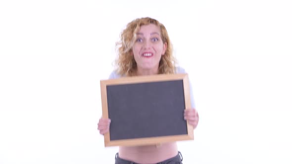 Happy Beautiful Blonde Woman Holding Blackboard and Looking Surprised