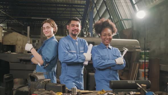 Multiracial workers collaborate and express happy work in a mechanical factory.
