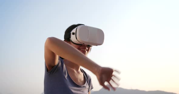 Woman playing with VR device at sunset time