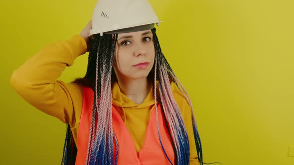 Female Construction Worker in Overalls on Yellow Background in Studio