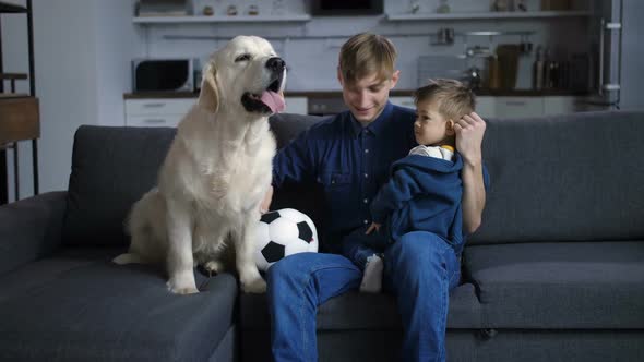Father with Toddler Son and Dog Sitting on Sofa