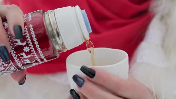 Young Couple Pouring Hot Tea From Thermos in Winter Day