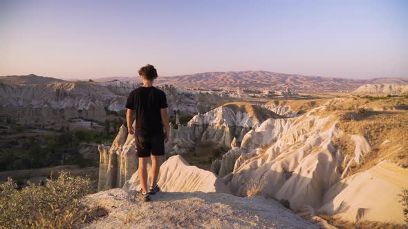 Young man walks towards a scenic viewpoint at sunset