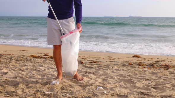 Mature Man Picking Up Trash At The Beach