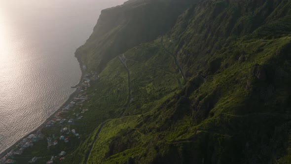 Dramatic mountainside towering above coastal village, Madeira; aerial