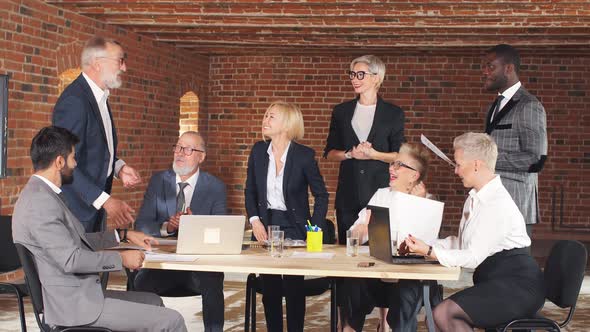 Group of Business People Greet a Female Leader in a Brick-walled Conference Room