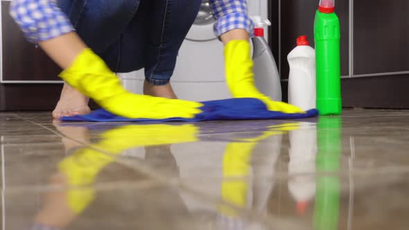 young woman in close-up washes squatting or kneeling on floor.