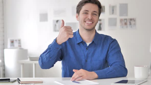 Thumbs Up by Casual Adult Man Sitting at Workplace