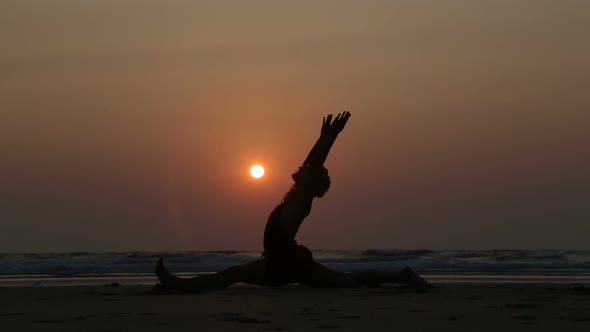 Man stretching at sandy beach in Goa at sunset.