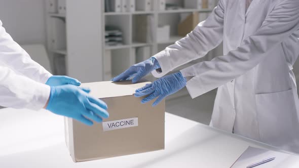 Unrecognizable Female Doctor Receiving Box of Vaccines