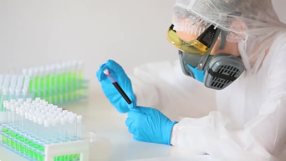 Close Up View of a Researcer in a White Overalls Looking on a Diseased Blood Sample in a Test Tube.