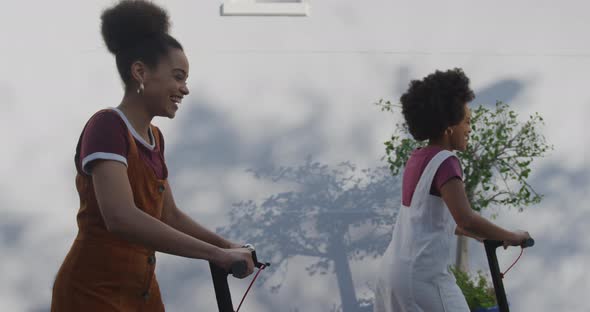 Two mixed race women riding electric scooter