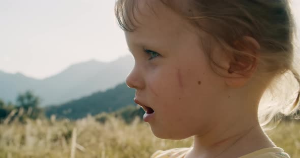 Closeup portrait of cute child girl stand on mountain meadow during summer trip