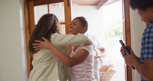 Group of diverse male and female friends welcoming each other in doorway