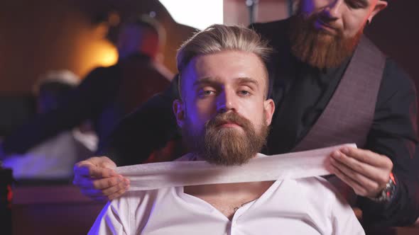 Stylish Male Barber Preparing Client for Cutting Beard