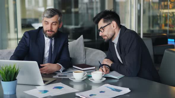 Mature Executives Negotiating Partnership in Cafe Looking at Laptop Screen