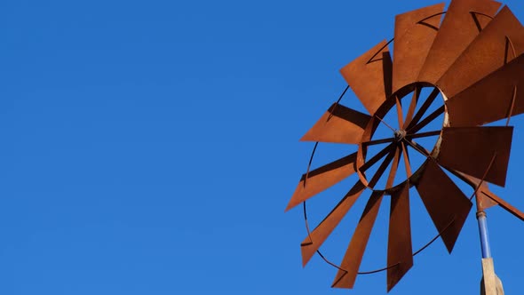 The Wind Pump Fan Blades are Moving Fast Against the Blue Sky