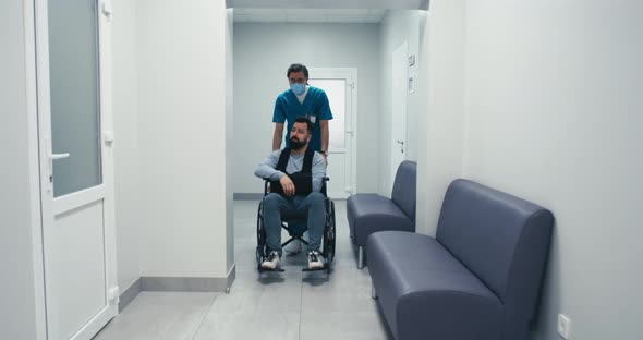 Handicapped Male Patient on Wheelchair Speaking with Doctor in Corridor