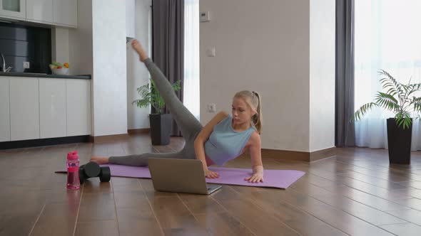 Woman Doing Exercises for Legs and Using Laptop