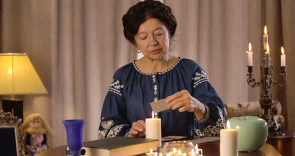 Old Caucasian Female Fortune Teller Taking Out Cards and Showing Ace of Spades To Camera